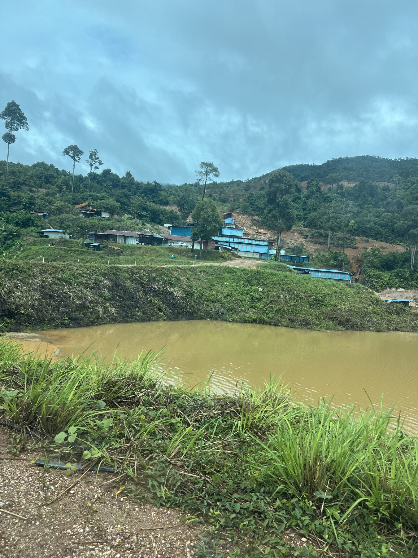 Bukit Kachi tin mining site overview in Malaysia — processing facility, settlement pond and surrounding mineral belt during an exploration site visit.
